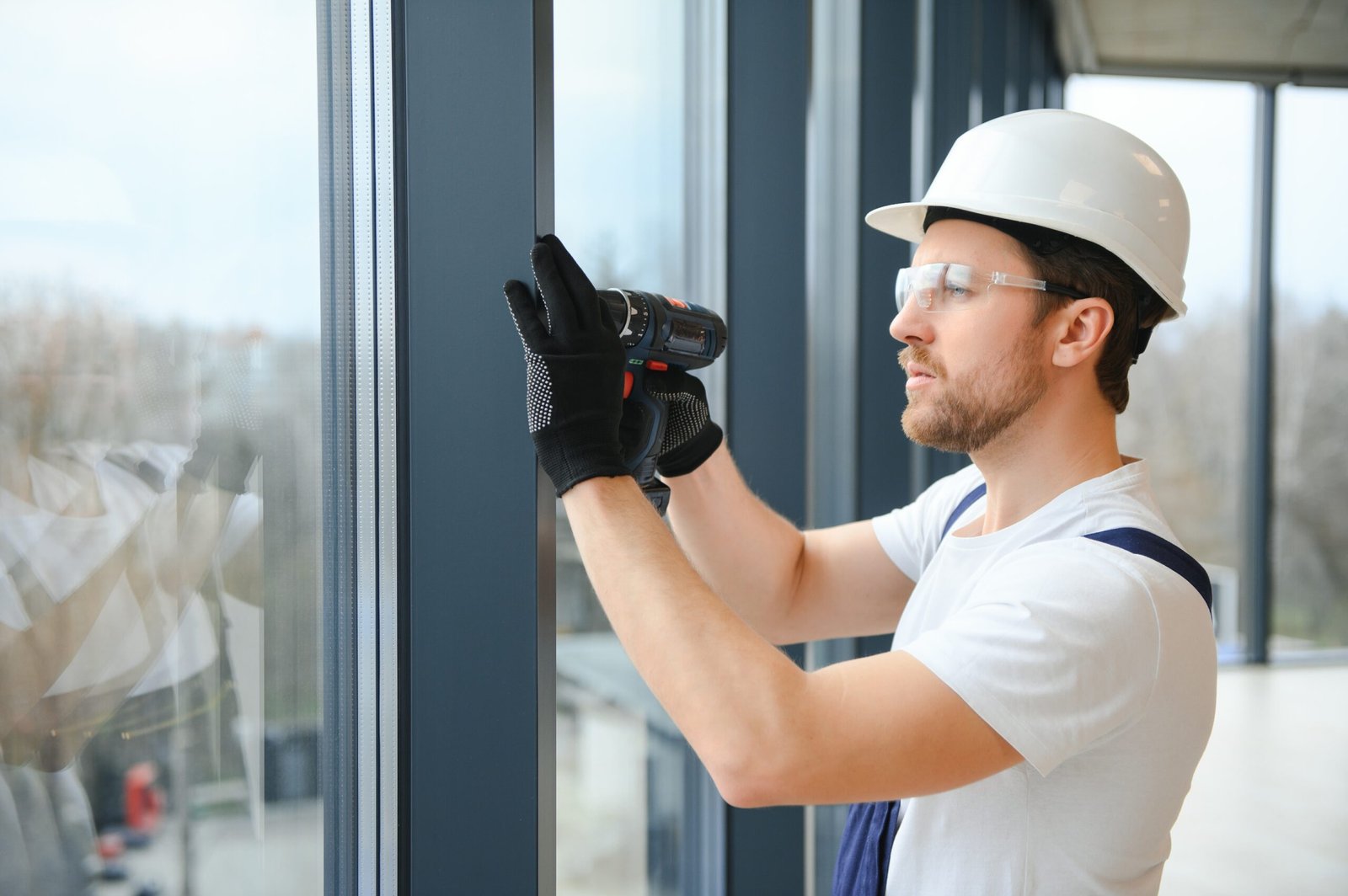 service man installing window with screwdriver.